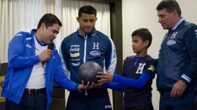 El presidente de Honduras, Juan Orlando Hernández (i), durante la entrega del balón de la paz del niño Lázaro González (2d) y ante al capitán de su selección de fútbol, Noel Valladares (2i), y al entrenador colombiano del equipo, Luis Suárez hoy, domingo 15 de junio de 2014, en Porto Alegre (Brasil).