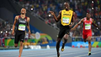Andre De Grasse y Usain Bolt ríen mientras llegan a la línea de meta de los 200 metros. Foto AFP