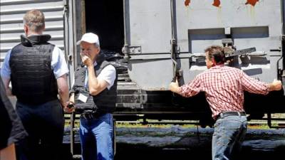 Inspectores de la OSCE, ante uno de los vagones refrigerados en los que se almacenan los restos de las pasajeros del avión. EFE