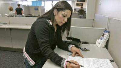 Una joven hispana rellena los formularios para solicitar un licencia de conducir en EUA. EFE/Archivo