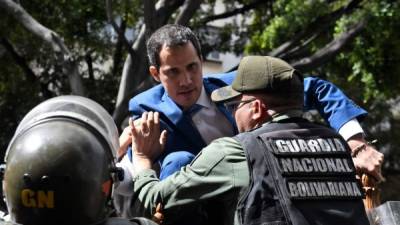 Venezuelan opposition leader and self-proclaimed acting president Juan Guaido tries to climb a railing in an attempt to reach the National Assembly building in Caracas, on January 5, 2020. - Venezuela's opposition lawmaker Luis Parra -a rival to Juan Guaido- declared himself parliament speaker, as Guaido and fellow opposition lawmakers were blocked from entering the National Assembly. Guaido had been expected to be re-elected parliament speaker but only regime lawmakers and opposition deputies critical of Guaido were allowed to enter the building. (Photo by Federico PARRA / AFP)