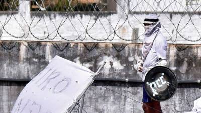 Un prisionero lleva un escudo con las iniciales de la banda delictiva PCC durante un motín en una cárcel de Natal, Brasil.
