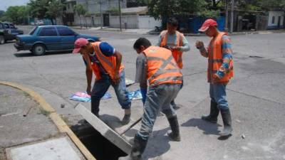 Hombres colocan una tapadera de concreto en una zona de San Pedro Sula.