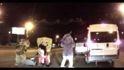 Se trata de 4 hombres que traen botargas de Mickey Mouse y Bob Esponja y otros personajes animados, quienes comienzan a golpear al automovilista.