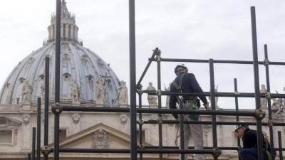 Varios empleados dan mantenimiento a la basílica en la plaza San Pedro.