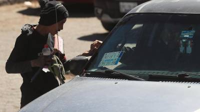 Un migrante recibe unas monedas por limpiar un vidrio en la fronteriza Ciudad Juárez, Chihuahua (México).