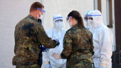 Personell of a mobile testing unit of the German Red Cross and the German army (Bundeswehr), prepare for testing the employees of the abatoir Toennies, at their residential homes in Verl, western Germany on June 23, 2020, amid the novel coronavirus pandemic. - German authorities ordered a new lockdown for the entire district of Guetersloh -- the first since easing coronavirus restrictions and a major setback for hopes of a swift return to normality. The lockdown would affect 360,000 people and would stay in place until at least June 30. (Photo by Ina FASSBENDER / AFP)