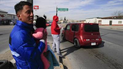 Migrante en México cargando en brazos a una niña pequeña | Fotografía de archivo