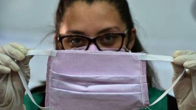 A worker of the Military Industry of the Armed Forces of Honduras, shows a face mask made for members of the Health sector who are in the front line in the fight against the novel coronavirus, COVID-19, in Tegucigalpa, on April 1, 2020. - The World Health Organization said Wednesday it was concerned about the recent 'rapid escalation' and global spread of the new coronavirus pandemic. (Photo by Orlando SIERRA / AFP)