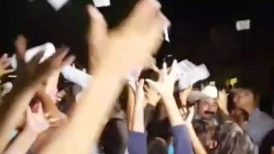 El alcalde de San Blas regalando billetes a los asistentes a su fiesta.