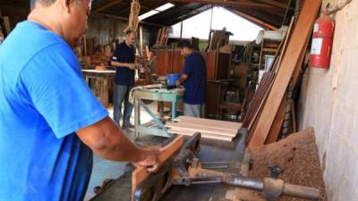 Tres hombres trabajan en un taller de ebanistería en el barrio Guamilito de San Pedro Sula.