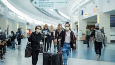 Las personas que usan máscaras protectoras caminan por la terminal del Aeropuerto Internacional de Jacksonville en Jacksonville, Florida. EFE