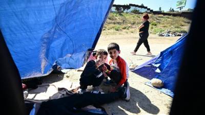 Los niños migrantes juegan mientras se refugian bajo lonas azules en la frontera entre Estados Unidos y México en San Diego, California.