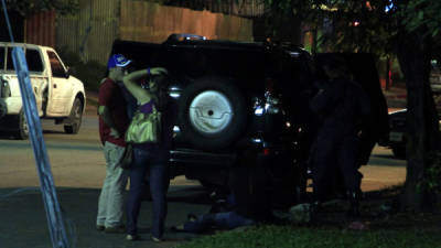 Amigos lamentan la muerte de David Ruiz, mientras policías revisan un carro.