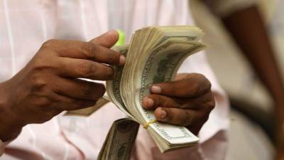 Un cambista cuenta un fardo de dólares. En 2001, el “pulgar” de CA sustituyó su colón por el billete verde.