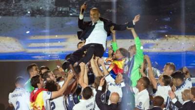 Real Madrid's French coach Zinedine Zidane is tossed by players as they celebrate the team's win, at the Santiago Bernabeu stadium in Madrid on June 4, 2017 after winning the UEFA Champions League football match final Juventus vs Real Madrid CF held at the National Stadium of Wales in Cardiff on June 3, 2017. / AFP PHOTO / CURTO DE LA TORRE