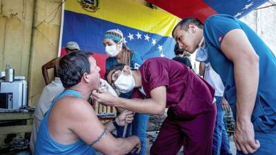 Miguel Gutierrez para The Wall Street Journal William Saavedra, un estudiante de ortodoncia, ofrece una consulta gratuita a un residente de bajos recursos del barrio 23 de Enero, en Caracas.