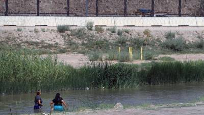 Fotografía en donde se ven dos mujeres migrantes mientras cruzan el río Bravo (río Grande), frontera natural entre Estados Unidos y México.