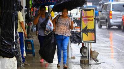 Mujeres caminan con sombrilla en el centro de San Pedro Sula.