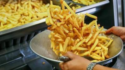 Un hombre remueve un recipiente lleno de patatas fritas. EFE/Stephanie Lecocq/Archivo