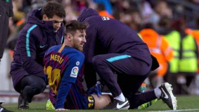 Lionel Messi, atendido por los médicos del Barcelona durante el partido ante el Valencia. Foto EFE