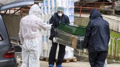 Trabajadores municipales con traje protector llevan el ataúd de una víctima del nuevo coronavirus en Macedonia. Foto: AFP