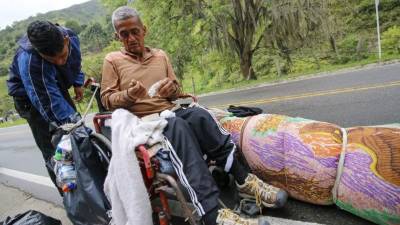 Jefferson Alexis, migrante venezolano, y su padre Jose Agustin Lopez, en una silla de ruedas, pararon para un pequeño descanso en el camino que de Cúcuta va a Pamplona, en el norte de Santander.