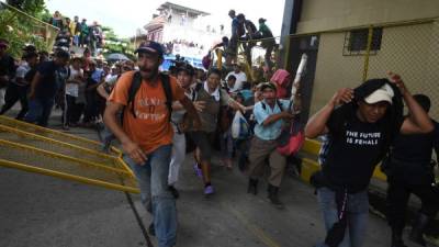 Momentos en que integrantes de la caravana de migrantes rompen el cerco de seguridad en la frontera de Guatemala para ingresar a México.