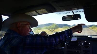 Jim Chilton señala desde su vehículo en una carretera hacia la frontera entre Estados Unidos y México de parte de su rancho de 50,000 acres el 14 de octubre de 2016. AFP