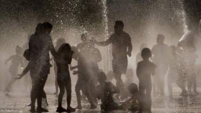 People cool off and sunbathe by the Trocadero Fountains next to the Eiffel Tower in Paris, on July 25, 2019 as a new heatwave hits the French capital. - After all-time temperature records were smashed in Belgium, Germany and the Netherlands on July 24, Britain and the French capital Paris could on July 25 to see their highest ever temperatures. (Photo by Bertrand GUAY / AFP)