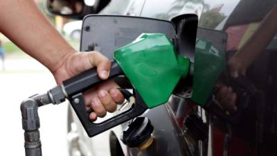 Un bombero de una estación de combustible llena el tanque de un carro.