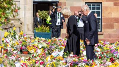 El rey Carlos III y su esposa observan las ofrendas florales para la reina Isabel II en las afueras del palacio de Buckingham.