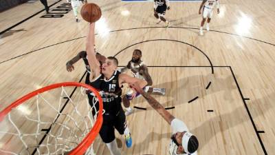 Nikola Jokic encesta la pelota para sumar dos puntos para los Nuggets durante el partido contra Lakers. Foto AFP