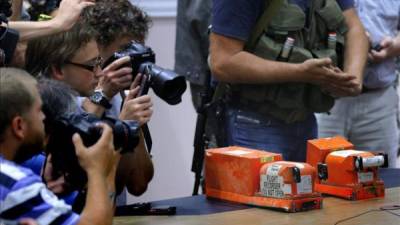 Periodistas toman imágenes de las dos cajas negras del vuelo MH17 de Malaysian Airlines antes de ser entregadas por separatistas prorrusos al coronel Mohamed Sakri (fuera de cuadro), del Consejo Nacional de Seguridad de Malasia. EFE