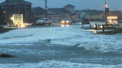 Ocean water rolls over NC 12 at the north end of Buxton, N.C. at dawn on Sunday, Oct. 28, 2012. Waves from offshore Hurricane Sandy are battering Hatteras Island. (AP Photo/The Virginian-Pilot, Steve Earley)