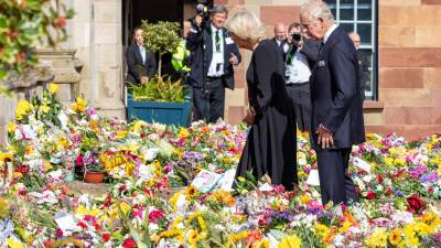 El rey Carlos III y su esposa observan las ofrendas florales para la reina Isabel II en las afueras del palacio de Buckingham.