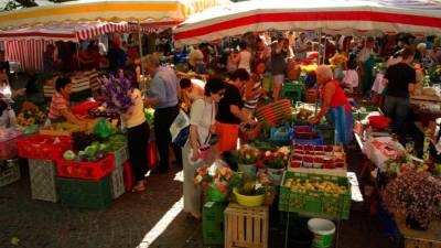Compradores en puestos de hortalizas y flores de un mercado en Río de Janeiro.