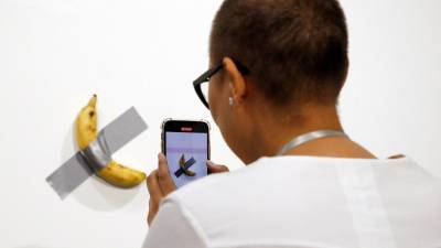 Una persona toma una fotografía de la obra 'Comedian', del artista italiano Maurizio Cattelan, durante el Art Basel en Miami, EE.UU., el 5 de diciembre de 2019.