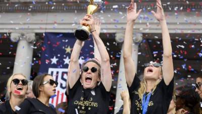 USA women's soccer player Megan Rapinoe (C) and other team members celebrate with the trophy in front of the City Hall after the ticker tape parade for the women's World Cup champions on July 10, 2019 in New York. - Tens of thousands of fans are poised to pack the streets of New York on Wednesday to salute the World Cup-winning US women's team in a ticker-tape parade. Four years after roaring fans lined the route of Lower Manhattan's fabled 'Canyon of Heroes' to cheer the US women winning the 2015 World Cup, the Big Apple is poised for another raucous celebration. (Photo by Johannes EISELE / AFP)