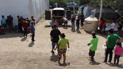 Migrantes que hacen fila para abastecerse de agua en un campamento a orillas del Rio Bravo donde se instaló un hospital móvil. Foto: EFE