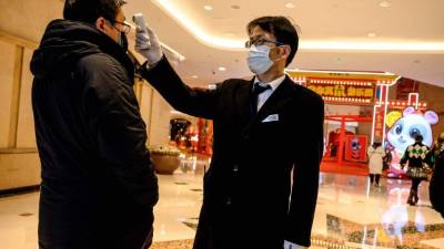 A security guard checks the temperature of a a man at a mall in Shanghai on February 8, 2020. - The new coronavirus that emerged in a Chinese market at the end of last year has killed more than 700 people and spread around the world. (Photo by NOEL CELIS / AFP)