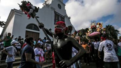 Feligreses pintados con aceite negro celebran frente a la iglesia de las Sierritas de Santo Domingo en Managua.