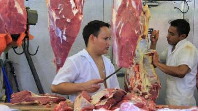 Dos jóvenes cortan una res en una carnicería del mercado Dandy de San Pedro Sula. La semana pasada hubo un incremento de tres lempiras por escasez de ganado.