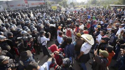 Riot police stand guard as teachers and supporters block access to Mexico City's Benito Juarez International Airport to protest education reform legislation in Mexico City on October 1, 2013. President Enrique Pena Nieto pushed through Congress changes to the constitution in December in order to put education, which was in the hands of powerful unions, back under government control and require teachers to undergo mandatory performance appraisals. Lawmakers are now debating legislation that would implement the new laws, which have prompted protests and strikes in some states. The teachers say the mandatory testing should only be used to help them improve, not to fire them or decide promotions. AFP PHOTO /ALFREDO ESTRELLA