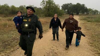 Un agente de la Patrulla Fronteriza carga a uno de los menores rescatados.