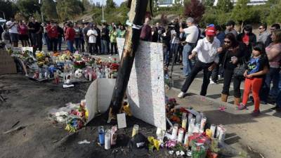 Aficionados se reúnen junto al memorial improvisado hoy, lunes 2 de diciembre de 2013, en el lugar donde falleció el actor estadounidense Paul Walker y el empresario de origen salvadoreño Roger Rodas en un Porsche Carrera GT rojo conducido por Rodas, el pasado sábado en Valencia (California). El accidente se registró durante un evento benéfico para la fundación Reach Out Worldwide, organizado con el fin de recaudar fondos destinados a los supervivientes del tifón Haiyan en Filipinas. EFE