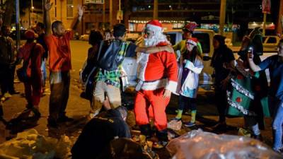 Un hombre vestido de Santa Claus reparte ropa y alimentos en las calles de Caracas.