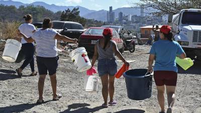 Capitalinos cargan baldes con agua después de obtener agua potable de un camión cisterna en las afueras de Tegucigalpa.