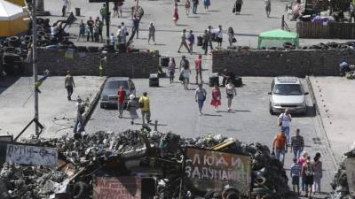 Varios ciudadanos caminan junto a las barricadas colocadas durante las protestas proeuropeas en contra del presidente depuesto Viktor Yanukovich en la Plaza de la Independencia en Kiev.