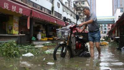 Un hombre conduce su motocicleta por las inundadas calles de Xiamen, provincia de Fujian, China.